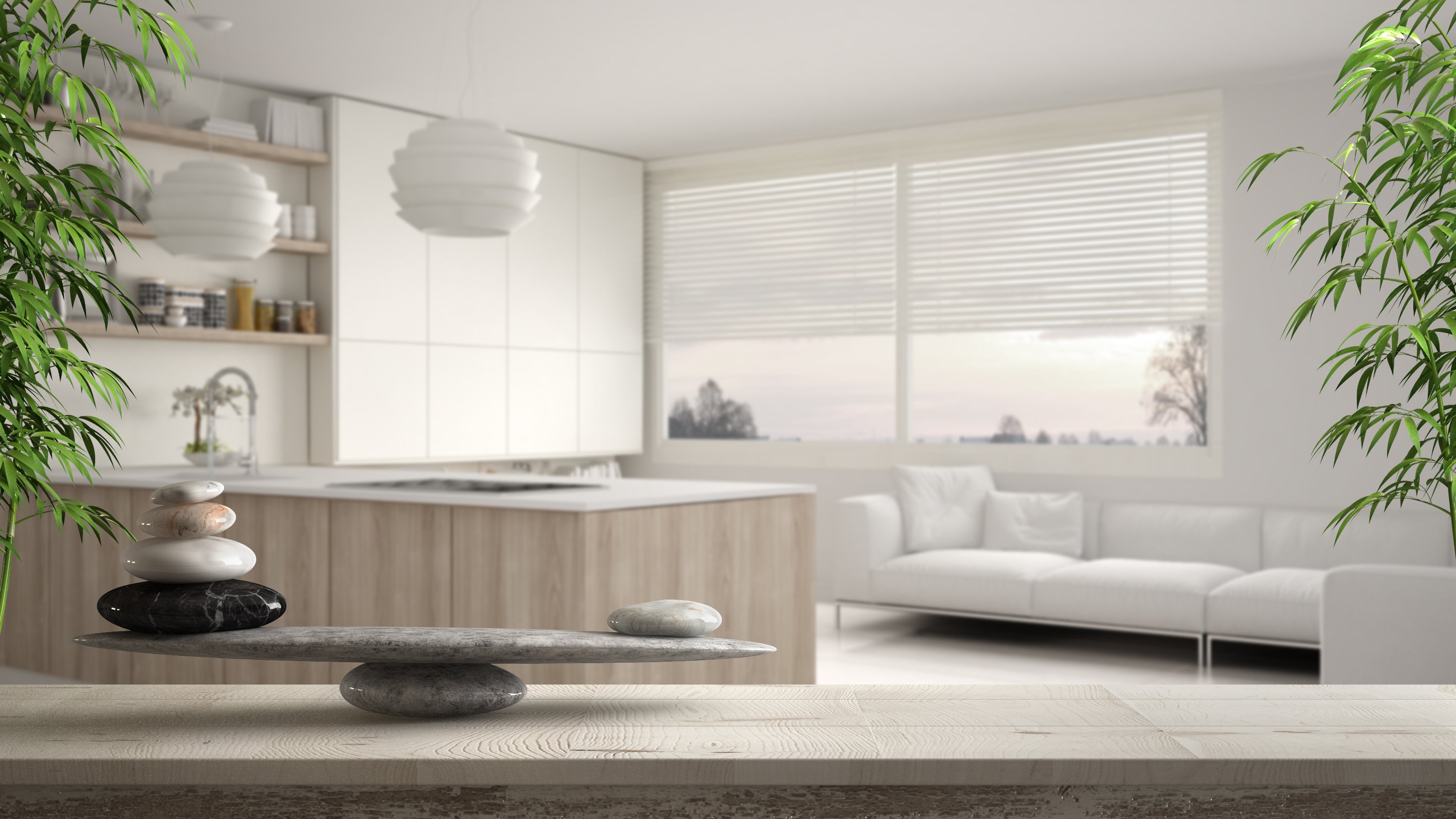 Wooden vintage table or shelf with stone balance, over blurred modern white and wooden kitchen with shelves and cabinets, feng shui, zen concept architecture interior design